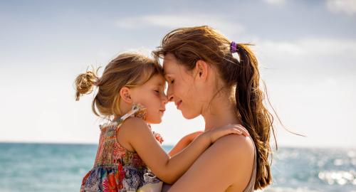 Madre e figlia abbracciate al mare, trasmettono amore e serenità.