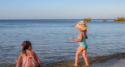 Bambine giocano felici in riva al mare, sole e libertà.